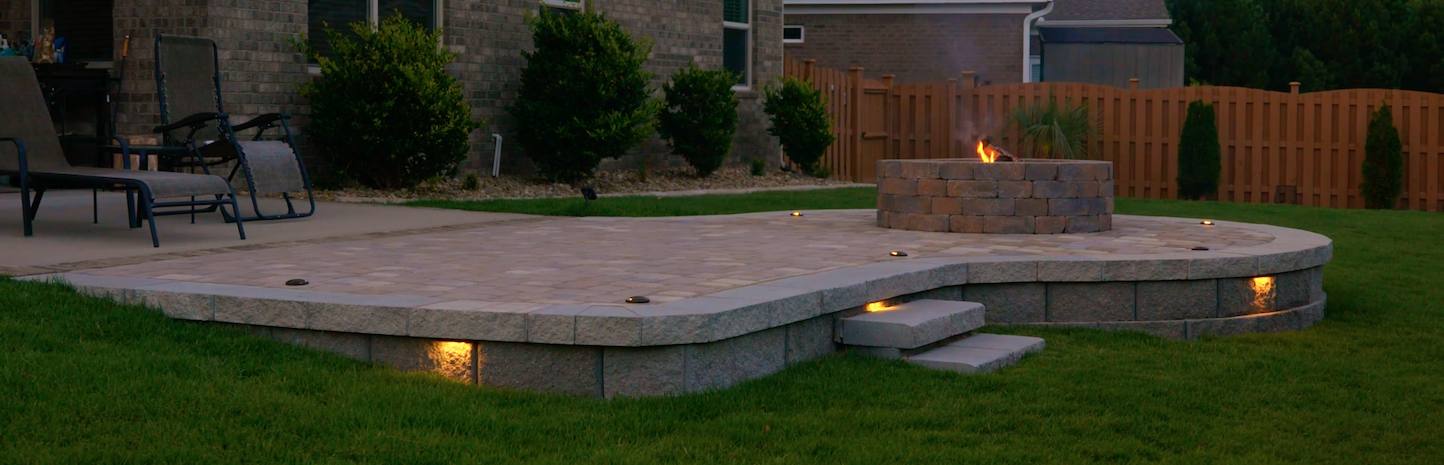Backyard stone patio at night with modern design
